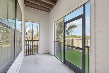 A balcony with a black railing and glass doors overlooking a green lawn at The Concord Luxury Apartments, Sarasota